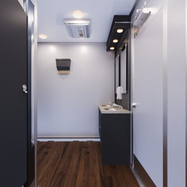 Interior of a luxury restroom trailer featuring a small sink with storage and a mirror in a compact space.